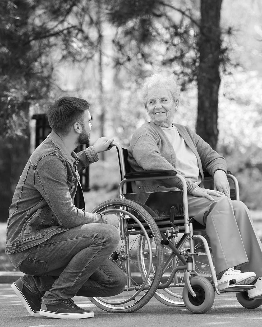 Pfleger geht mit Seniorin im Rollstuhl spazieren